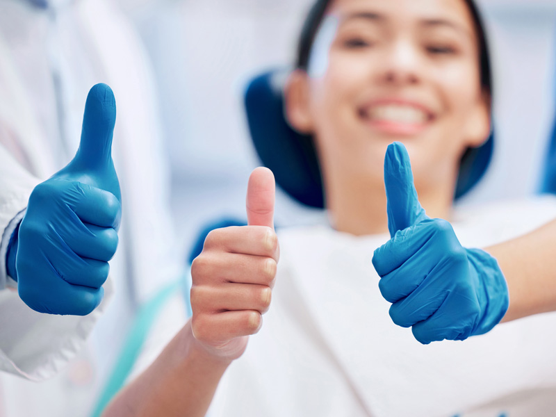 lady smiling in dental chair with thumbs up