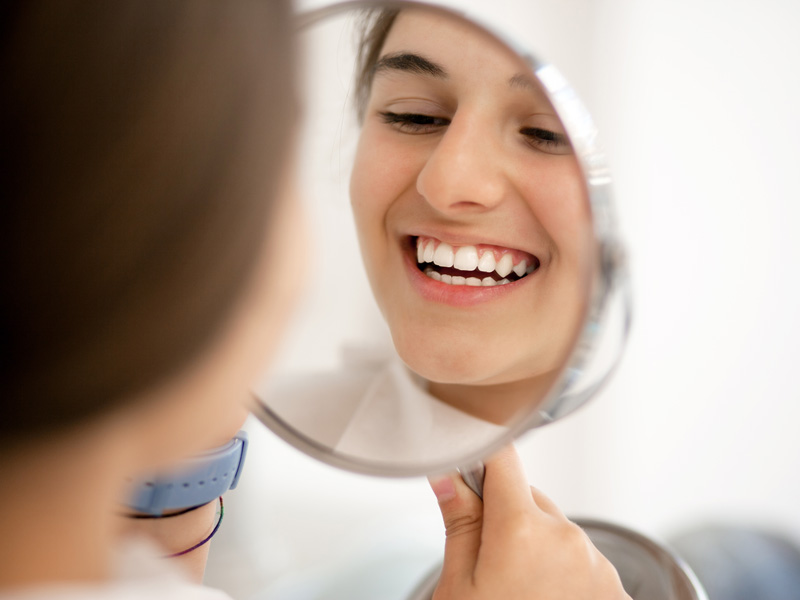 lady smiling holding a mirror